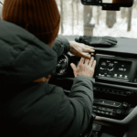 Person checking the vehicle air conditioner controls on the dashboard inside a car.