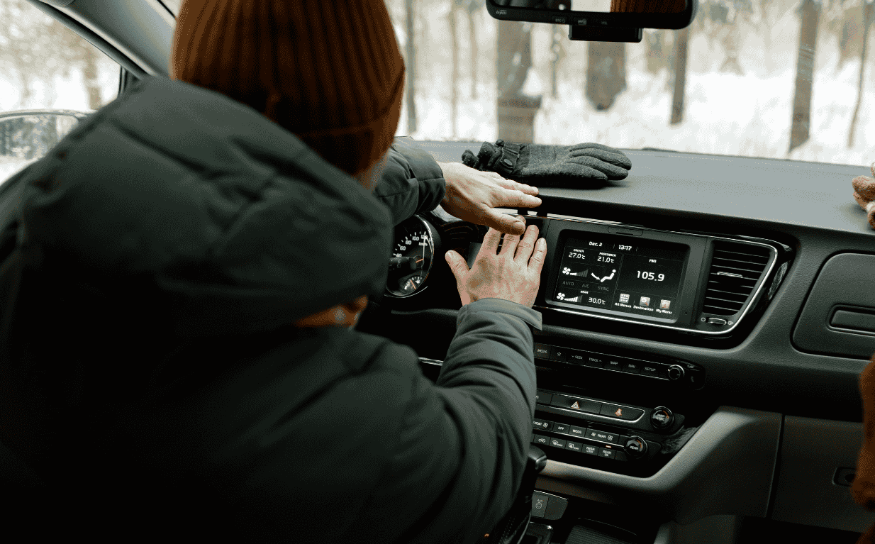 Person checking the vehicle air conditioner controls on the dashboard inside a car.